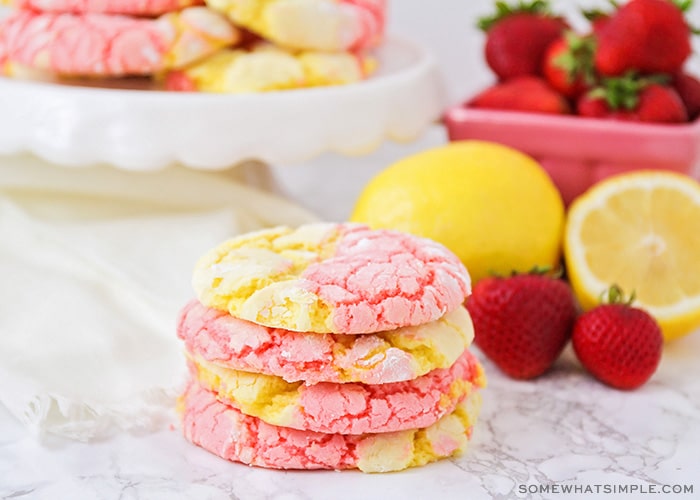 a stack of strawberry lemonade cookies on a counter next to strawberries and lemons