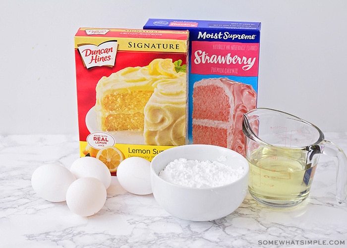 a box of duncan hines lemon cake mix, a box of pillsbury strawberry cake mix, eggs, a bowl of powdered sugar and oil on a counter