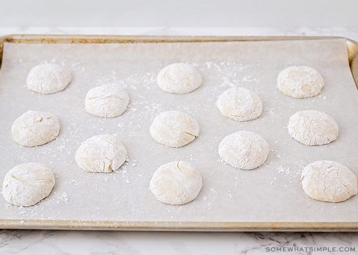 balls of cookie dough covered in powdered sugar layed out on a baking sheet