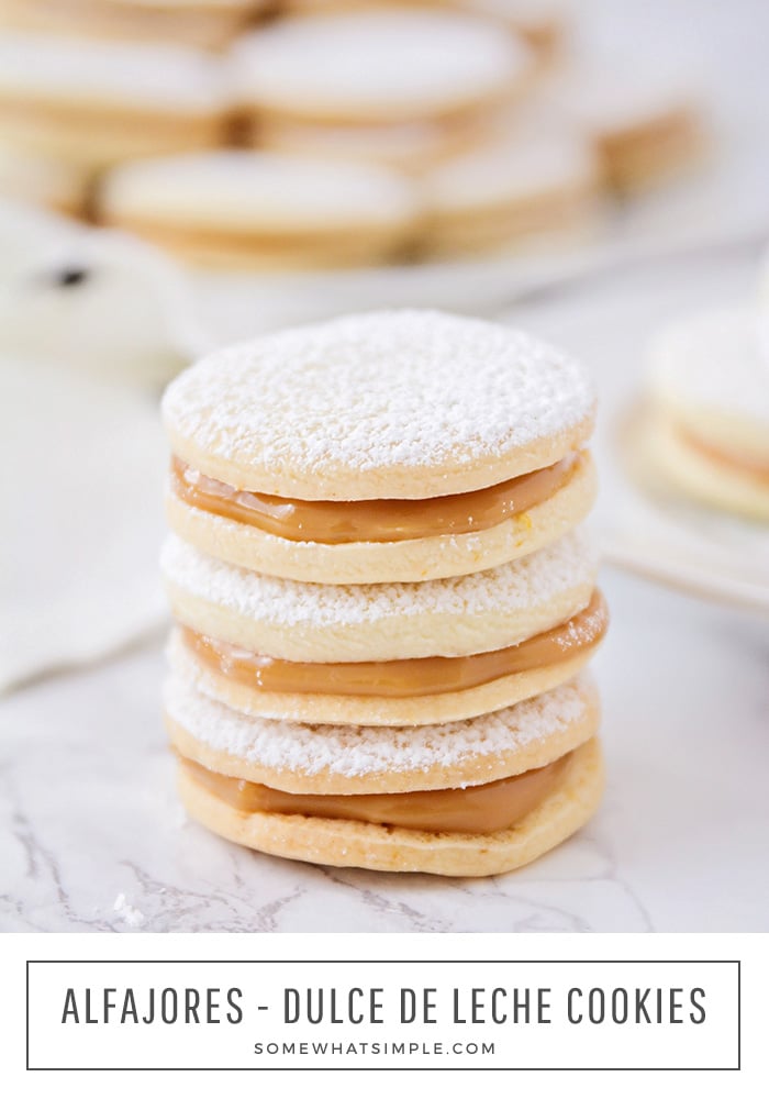 une pile de 3 biscuits alfajore empilés les uns sur les autres et saupoudrés de sucre en poudre.