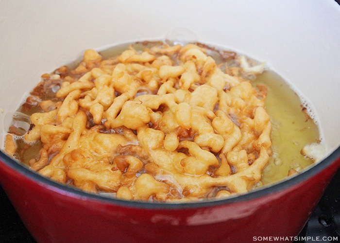 a funnel cake cooking in a large pot of oil