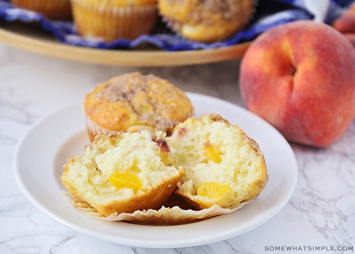 a freshly baked muffin with peach chunks inside and topped with a streusel topping