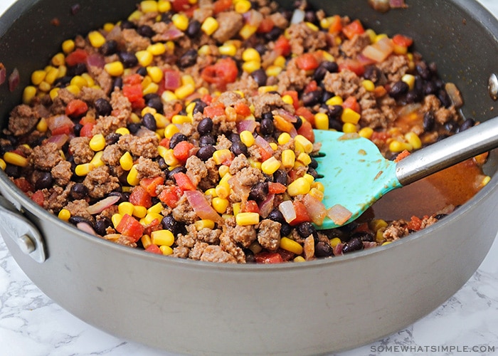 a skillet filled with ground beef, corn, black beans and tomatoes