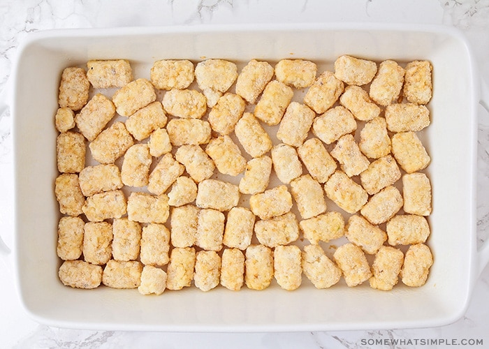 a layer of frozen tater tots at the bottom of a casserole pan