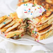 a stack of cake mix pancakes topped with whipped cream and sprinkles