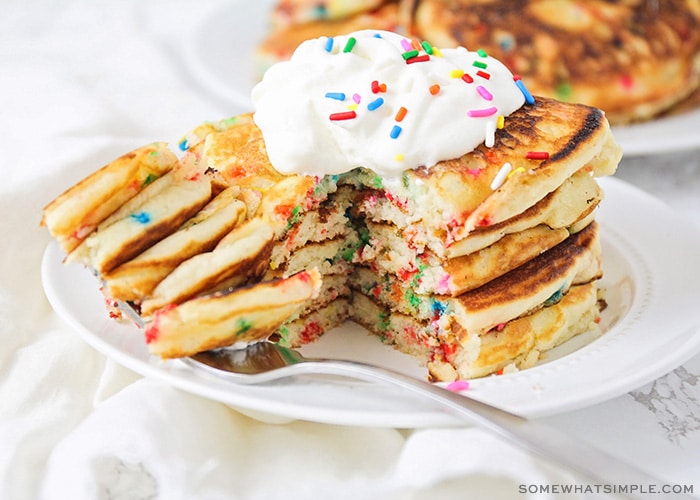 a stack of cake mix pancakes topped with whipped cream and sprinkles