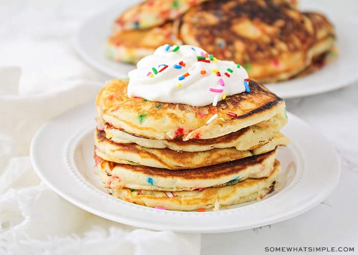 fluffy pancakes topped with whipped cream and sprinkles