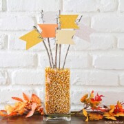 a fall centerpiece made with pennants and twigs on a table