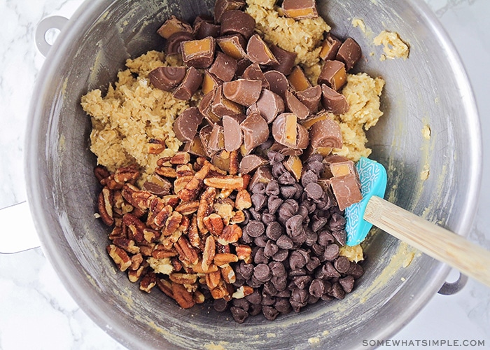 looking down on a bowl filled with cookie dough, chocolate, caramel and pecans