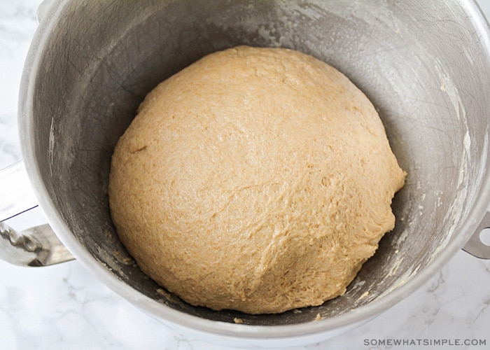 a ball of whole wheat bread dough in a mixing bowl