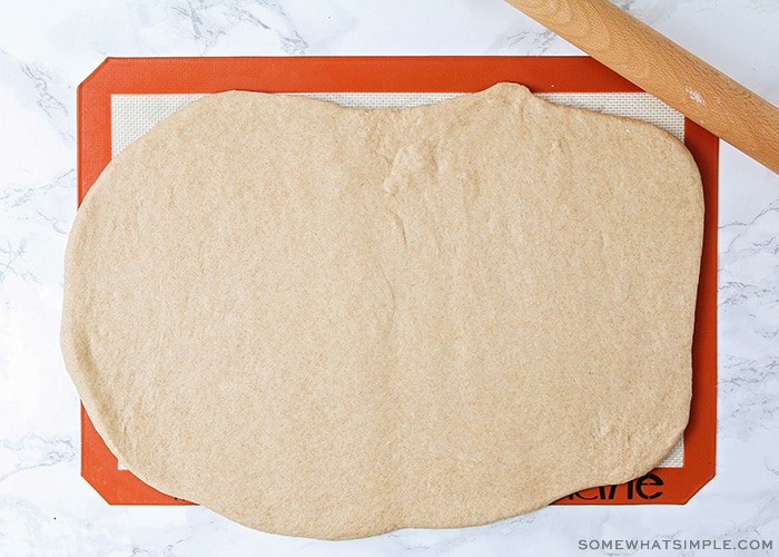 wheat bread dough rolled out on a baking mat