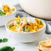 White Chicken Chili in a white bowl with ingredients in the background