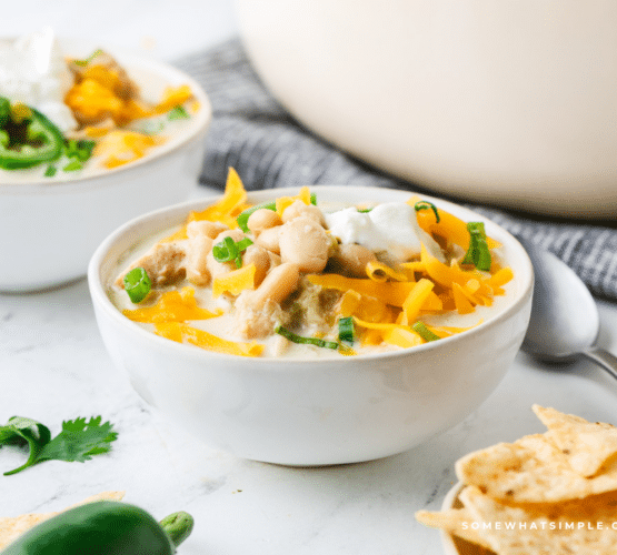 White Chicken Chili in a white bowl with ingredients in the background