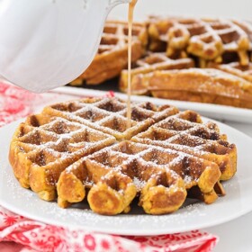 cinnamon syrup being poured over gingerbread waffles