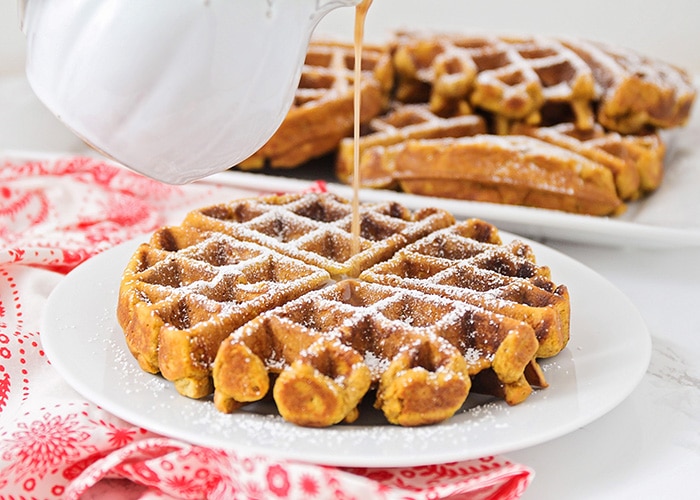 cinnamon syrup being poured over gingerbread waffles