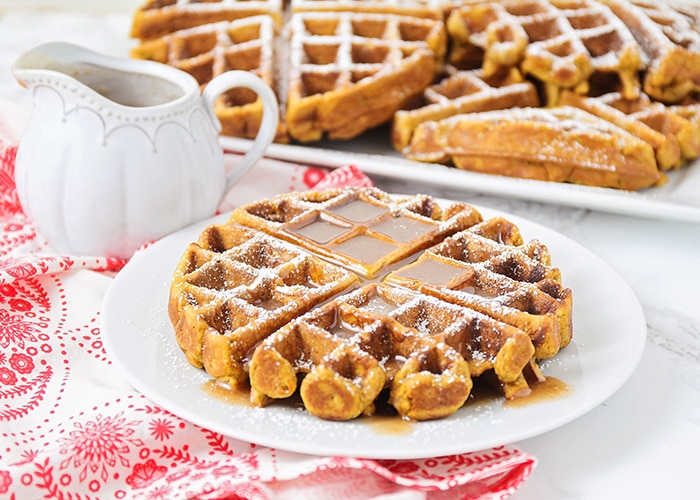 a gingerbread waffle dusted with powdered sugar and topped with syrup