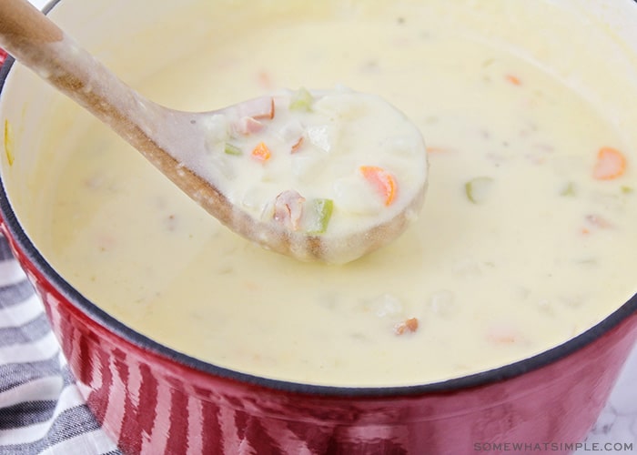 a ladle over a pot filled with ham and potato soup