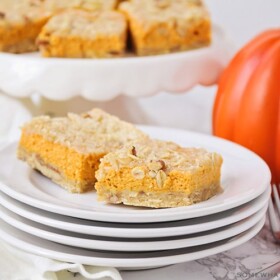 two squares of pumpkin pie bars on a stack of plates