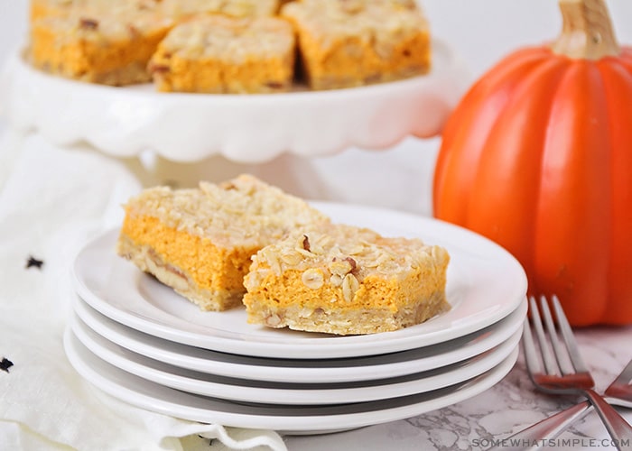 two squares of pumpkin pie bars on a stack of plates