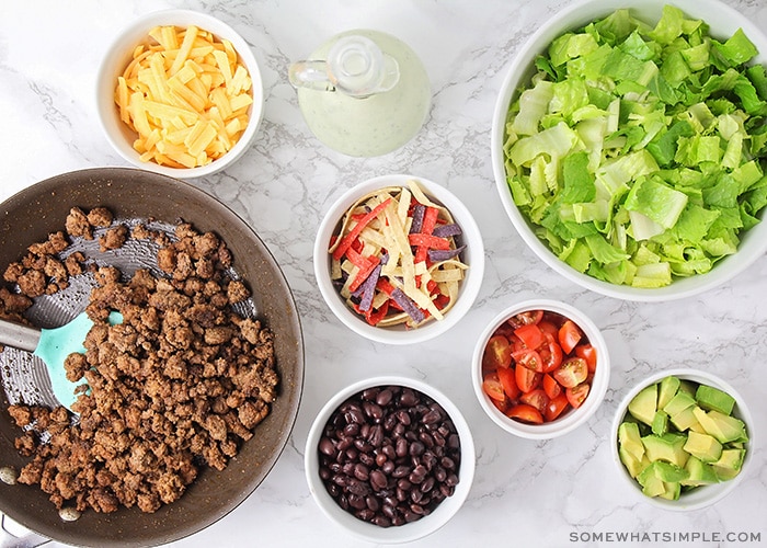 looking down on small bowls filled with taco salad ingredients