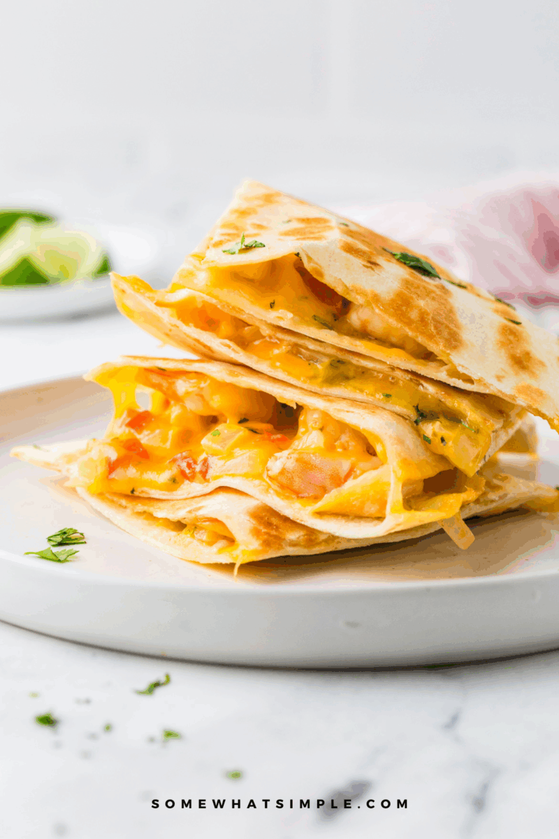 close up shot of Shrimp Quesadillas stacked on top of each other, showing the melted cheese and fillings