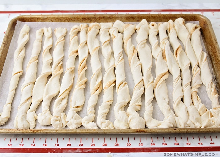 raw dough twisted and laying on a baking sheet