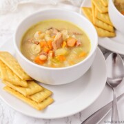 A bowl of soup filled with ham, white beans and vegetables