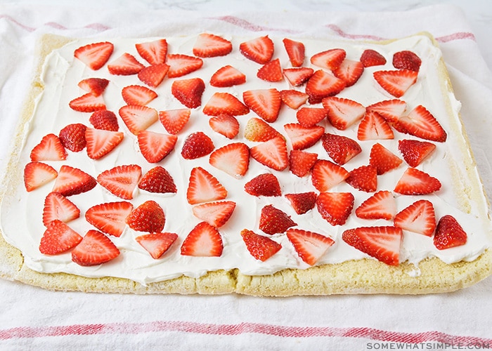 a rectangle cake with a cream cheese filling and sliced strawberries on top