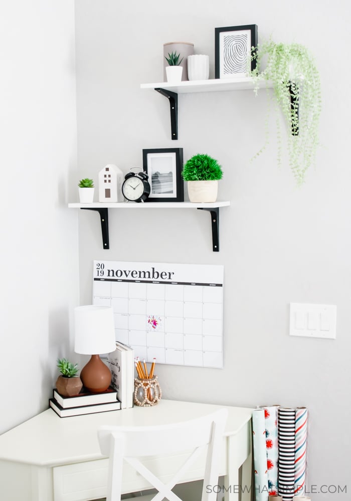 shelves with decorations on a wall with a small corner desk below them