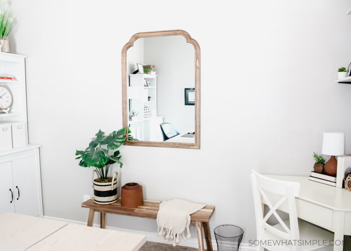 a mirror on a wall next to a white corner desk