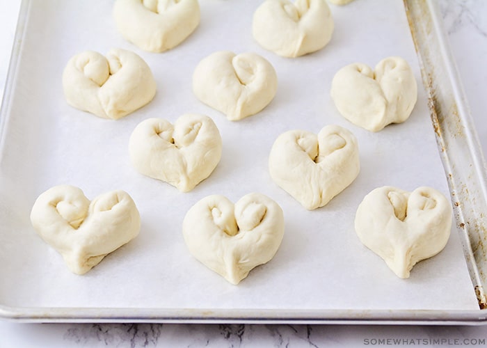 raw heart shaped bread dough on a baking sheet