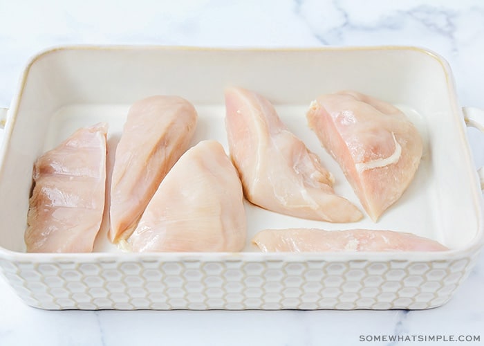 a baking dish filled with raw chicken breasts