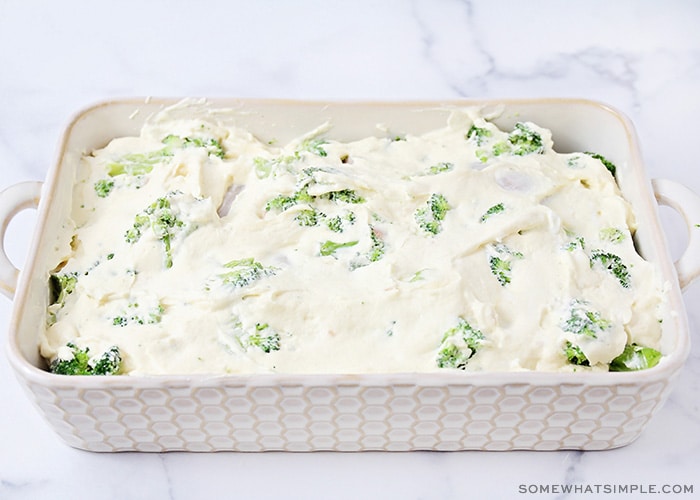 an baking pan filled with chicken, broccoli and topped with a creamy mayo sauce