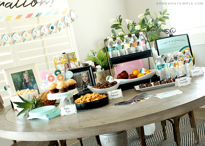 Grad party set up with finger foods and rainbow decorations. 