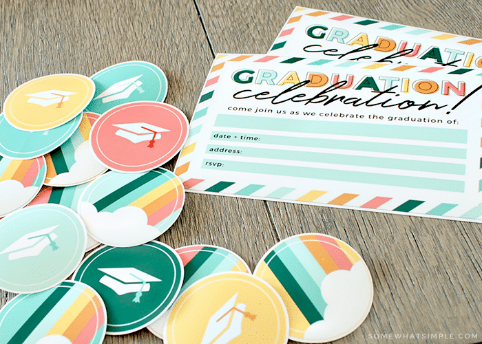 Graduation Celebration invites and cupcake toppers laying on a wood table