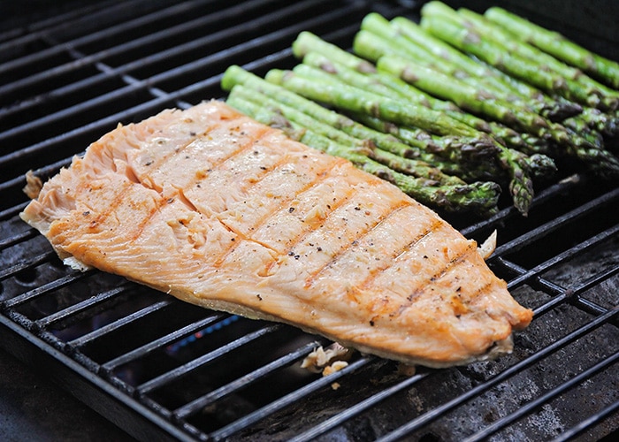 grilled salmon on the grill next to asparagus stalks