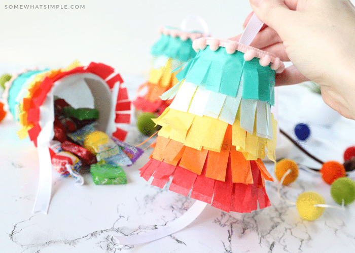 holding a pinata made from a paper cup