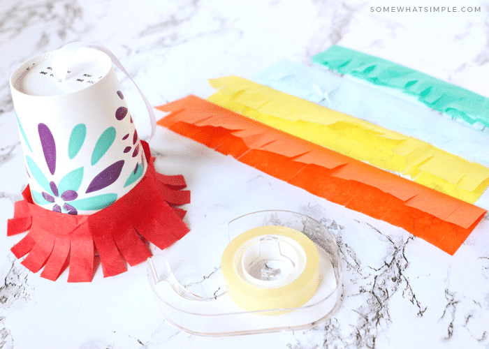 wrapping strips of tissue paper around a paper cup