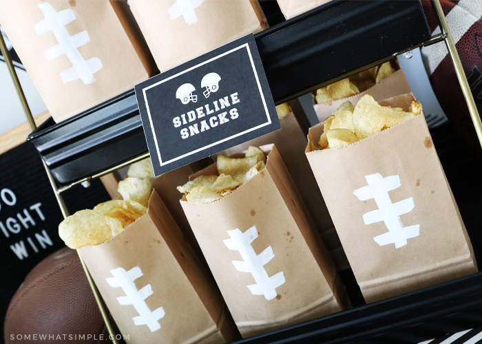 brown paper bags with white tape in the design of football laces filled with chips