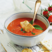 tomato basil soup in a white bowl with crutons in the middle