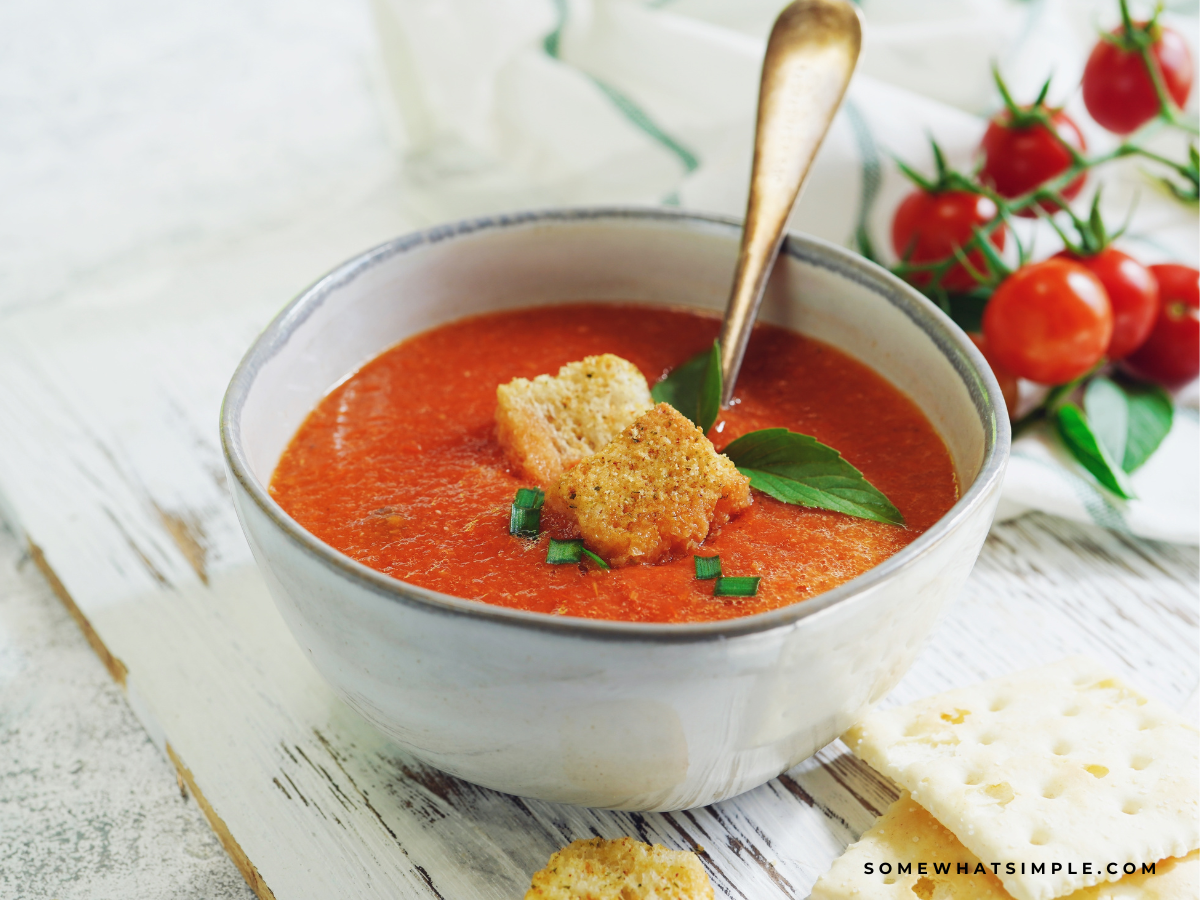 tomato basil soup in a white bowl with crutons in the middle