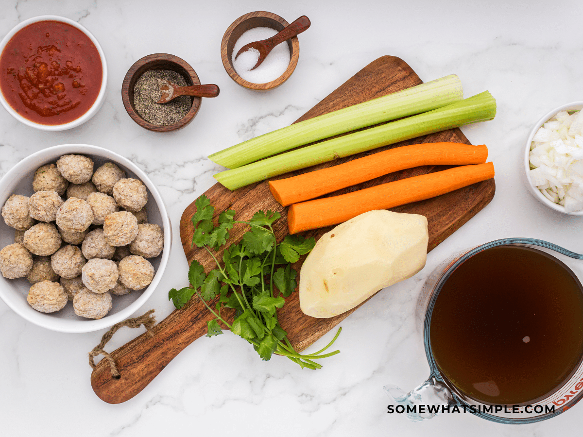 Ingredients to make Albondigas soup on white counter.