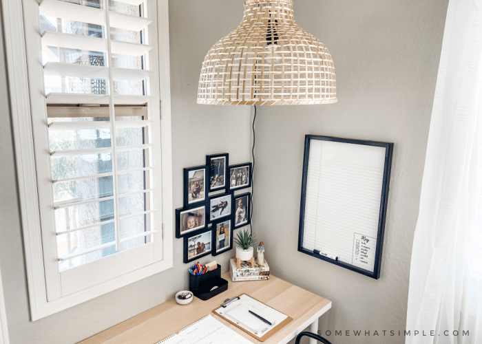 Teenagers desk with light wood top, a black collage of frames and a white board