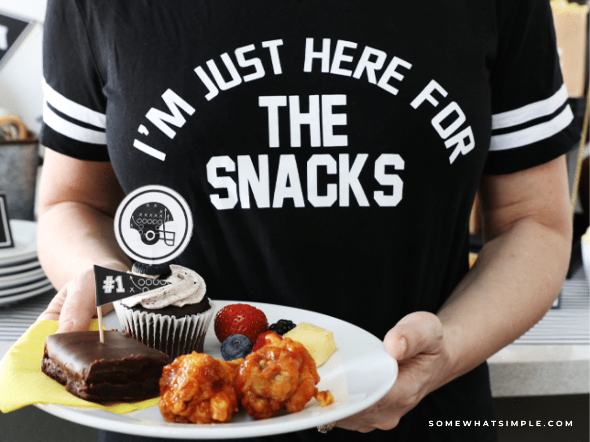 close up of a woman holding a plate of snacks wearing a shirt that says, "I'm just here for the snacks"