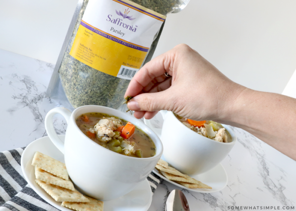 sprinkling parsley on chicken soup