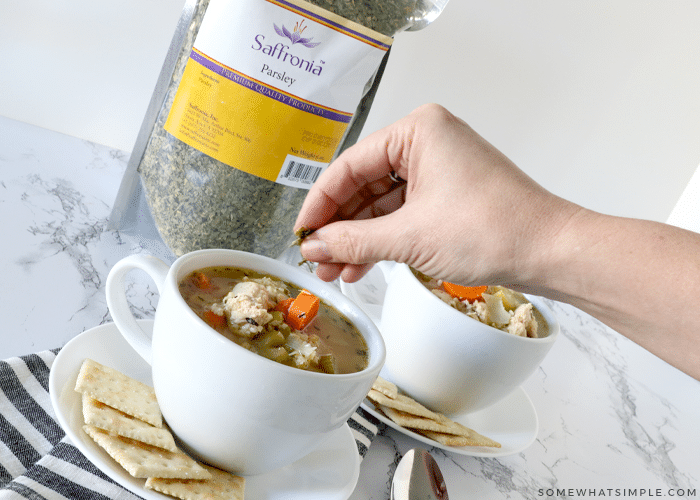 sprinkling parsley on chicken soup