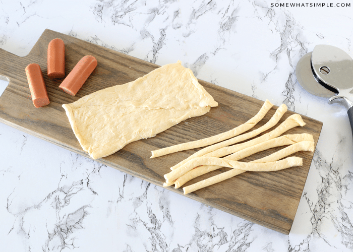 hot dogs and crescent rolls on a cutting board