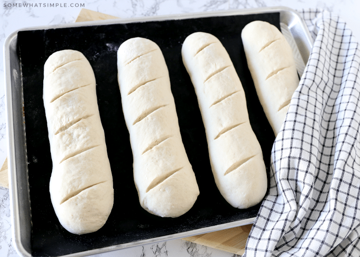 4 loaves of french bread dough on a baking sheet