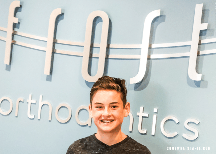 Boy with braces standing in front of orthodontist office