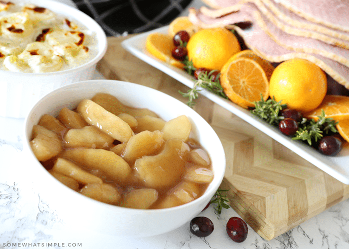 cinnamon apples in a bowl surrounded by food for the holidays